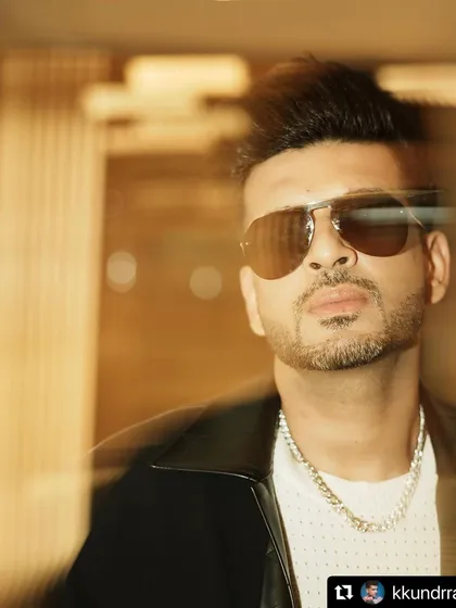 A close-up portrait of Karan Kundrra. The combination of the textured shirt, chain, and sunglasses creates a look that is both relaxed and sophisticated.