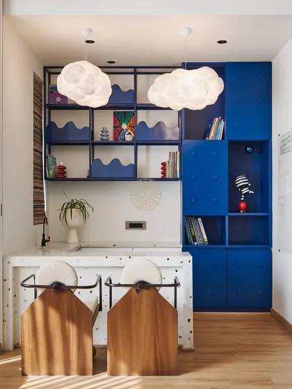 This activity area was designed to inspire play. It includes a counter for games, Lego-inspired blue storage for artwork, and whimsical cloud-shaped pendant lights.