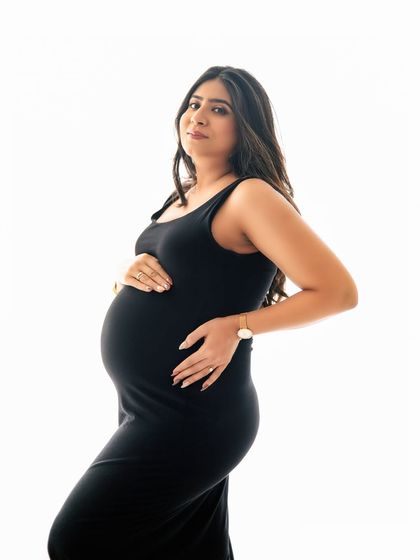 A simple black dress against a clean white background creates a powerful and timeless maternity portrait. This style is perfect for highlighting your beautiful bump with classic elegance.