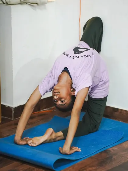 A student practices a deep wall-supported backbend, showcasing the flexibility and strength developed through our Hatha yoga training.