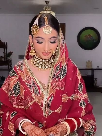 A beautiful bridal portrait showcasing a sleek bun and a statement maang tikka. This clean hairstyle ensures the focus remains on the bride's features and stunning jewelry.