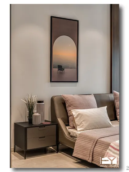 A modern bedroom with a soft, moody ambiance. The artwork above the bed depicts a solitary chair at sunset, echoing the room's tranquil and contemplative feel. The color palette is warm, with shades of dusty rose and taupe.