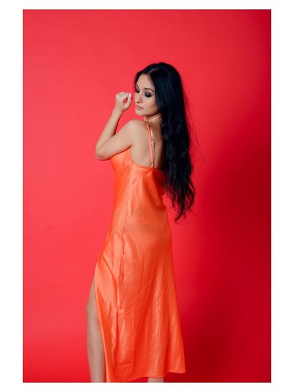 A glamorous portrait in a vibrant orange dress. The pose is elegant and the color is eye-catching.