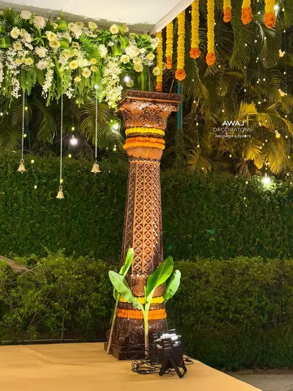 A detail of one of the intricately carved pillars of the mandap, adorned with marigold garlands and banana leaves for auspiciousness.