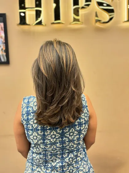 A full back view of a client's hair, showcasing the beautiful blend of highlights and the precision of the layered cut.