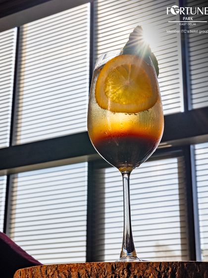 The sunlight filtering through the blinds creates a beautiful play of light and shadow on this artfully presented cocktail.