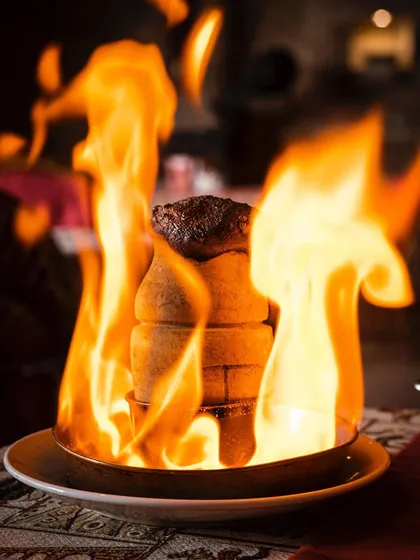 The pottery kebab dramatically set on fire at the table. This shot is all about capturing the theatrical dining experience.