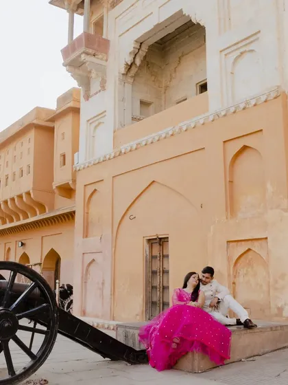 A romantic moment next to a historic cannon at Amber Fort. This unique composition adds a touch of historical drama to the couple's pre-wedding album.