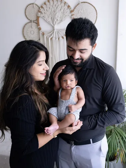 An intimate family moment. The parents gaze lovingly at their newborn, who is held securely in their hands, creating a beautiful portrait of a new family.