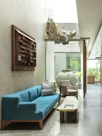 The ground floor lounge at the Bammi Residence, a space designed for a multi-generational family. It features a custom blue sofa, a Shola art coffee table, and a hanging light installation by Ankon Mitra.