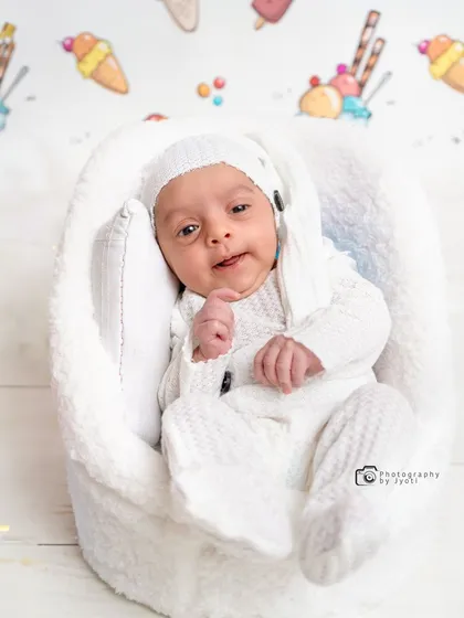 A sweet close-up of a newborn baby in a white knitted outfit. I focus on capturing their delicate features and innocent expressions during these early days.