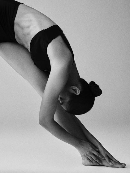 A close-up on a deep forward bend, creating a beautiful abstract shape. The focus is purely on the lines and curves of the body.