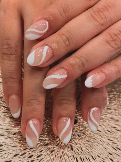 A duplicate of image 41, showing a chic and modern design on short, almond-shaped nails with a sheer nude base and bold white swirls.