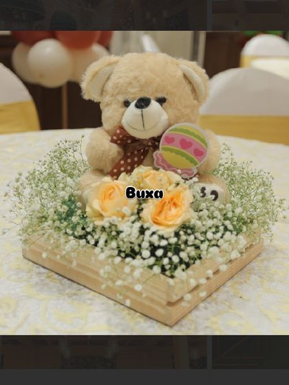 A sweet teddy bear and floral arrangement in a pinewood box, designed as a table centerpiece for a "bearly wait" baby shower.