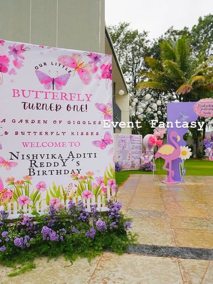 The entrance to Nishvika's butterfly garden party, with a welcome sign framed by beautiful purple flowers.