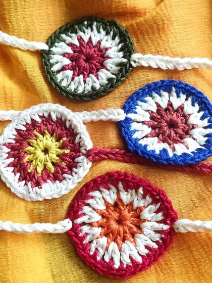 Four variations of our 'charkha' style crochet rakhis, each with a unique color combination. You can pick your brother's favorite color for a personalized touch.