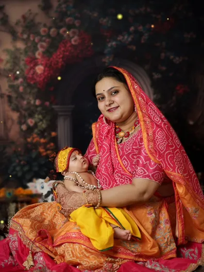 A mother holds her newborn, both dressed for a Janmashtami celebration. It's never too early to start creating these beautiful cultural memories with your little one.