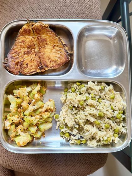 This plate features pea pulav with a large piece of pan-fried kingfish and a side of sautéed bottle gourd.