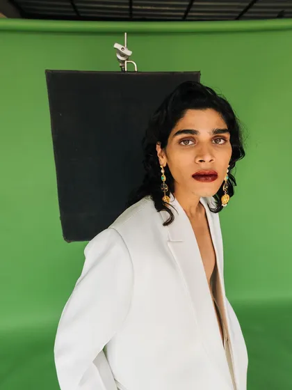 A wider shot from the Amama Jewels campaign, showing the model in a white blazer against the green screen studio setup. It provides context to the creative process.
