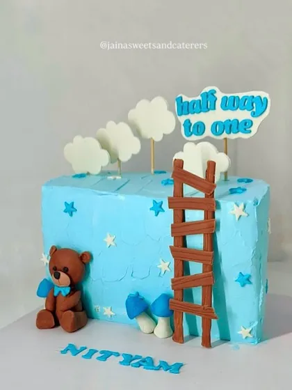 Celebrating a big milestone: halfway to one. This adorable 6-month birthday cake is designed with a cute teddy bear, fondant clouds, and a ladder, symbolizing the climb to the first birthday.