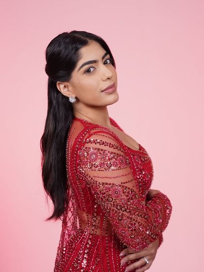 A close-up of the red three-piece Indo-Western set, focusing on the intricate beadwork and the confident pose.