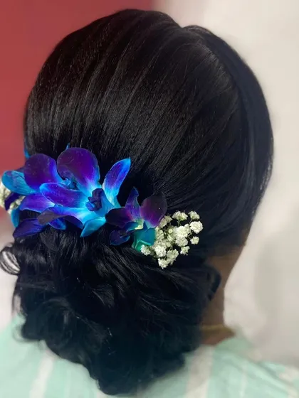 A side profile of the elegant low bun, showing the soft, swept-back front and the beautiful floral arrangement.