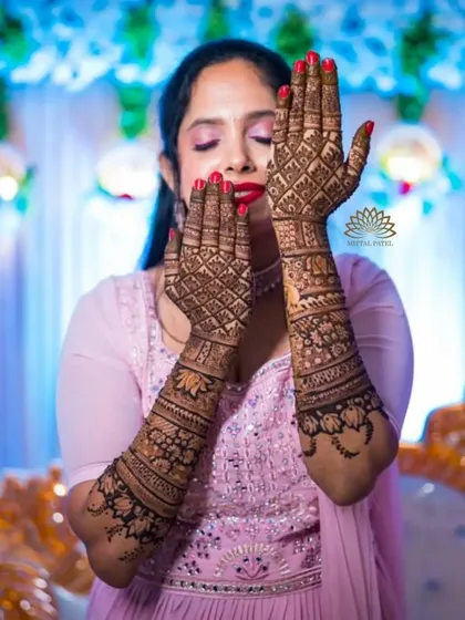 A happy bride showing off her full bridal mehndi. The design is intricate and the stain is dark, a perfect combination for her big day.