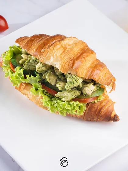 The Pesto Chicken Croissant Sandwich. Tender chicken tossed in aromatic pesto, layered with fresh vegetables inside our signature croissant for a flavourful and satisfying meal.