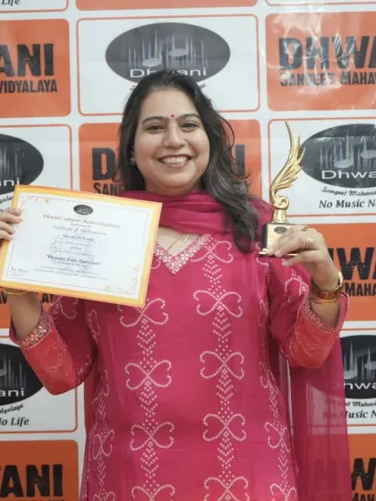 An adult student joyfully holds her certificate and trophy.