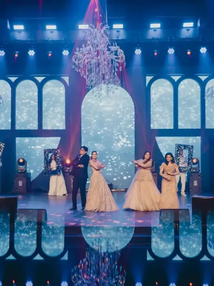 A wide shot of the couple's Sangeet performance, showing the scale of the stage, the LED backdrop, and the dramatic lighting design.