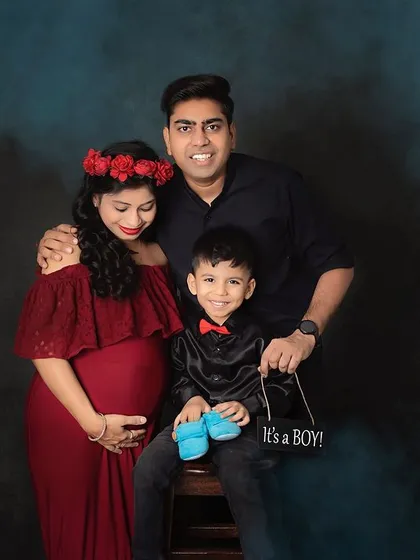 A beautiful family portrait announcing their baby boy. The older brother looks so proud, and the mom-to-be is stunning in a red gown with a floral crown.