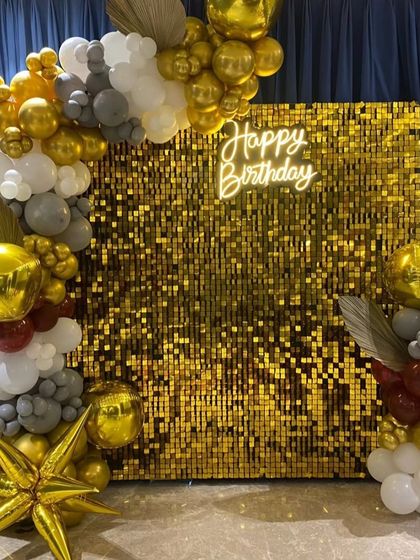 A different angle of the glamorous gold shimmer wall birthday setup, showing the balloon details.
