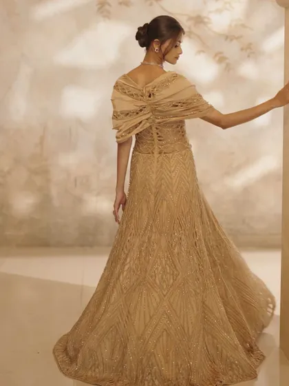 The back view of the golden gown, revealing the detailed corset tie-up and the elegant drape of the bodice.