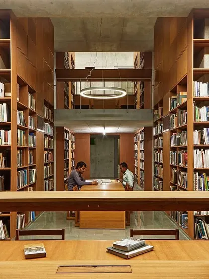 We design libraries as sanctuaries for knowledge and quiet contemplation. At the Lilavati Lalbhai Library at CEPT University, floor-to-ceiling wooden bookshelves create a warm, immersive environment, with carefully planned sightlines that draw the eye through the multi-level, subterranean space.