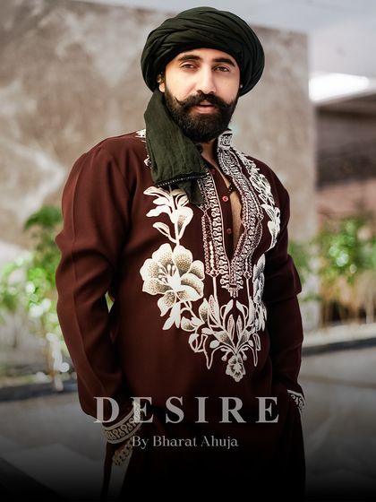 The intensity of the gaze is matched by the boldness of the garment. The contrast between the deep maroon fabric and the bright white embroidery makes this kurta a piece of statement ethnic wear.