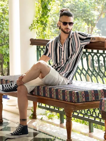 A relaxed summer look for Camla Barcelona, featuring a striped resort shirt and white shorts. The styling with high-top sneakers and sunglasses creates a cool, casual, and on-trend vibe.