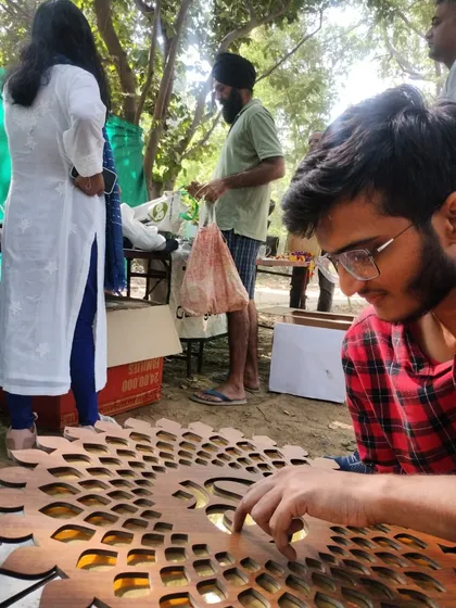 A volunteer carefully inspects a decorative wooden panel at our 'Purana Baksa' stall. We ensure all items are in good condition before offering them to the community.