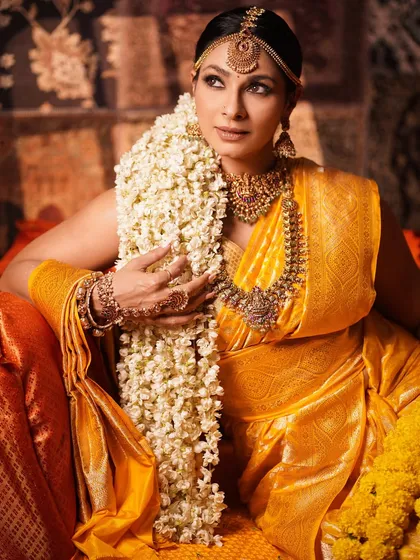 A side profile of Tanishaa Mukerji, highlighting the long jasmine gajra and the intricate details of her traditional attire. The lighting creates a warm, golden glow.