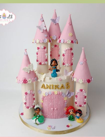 A fairytale princess castle cake for a 5th birthday. This grand pink castle is home to several Disney princesses, including Jasmine, Tiana, and Ariel, ready for a royal celebration.
