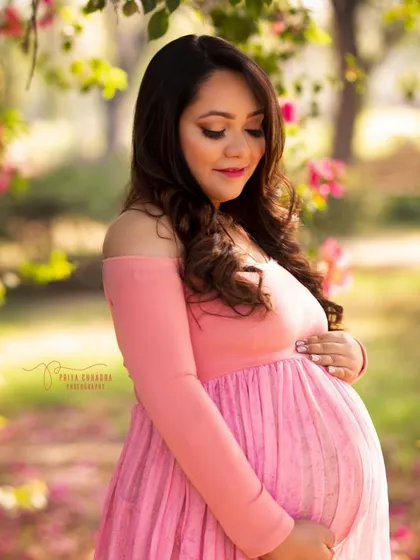 Pretty in pink, surrounded by blossoms. This outdoor portrait captures the soft, gentle side of motherhood, with a beautiful natural background that enhances the pregnancy glow.