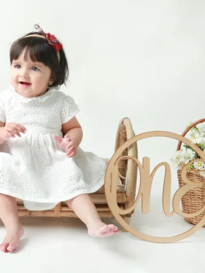 This little girl is all smiles as she sits on a miniature cane bed, celebrating her first birthday in style.