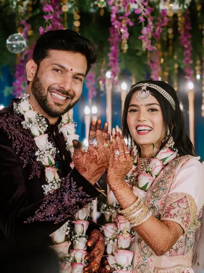 A joyful shot of the newly engaged or married couple showing off their rings with big smiles.