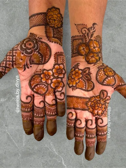 A vibrant and full floral mehendi design. This pattern combines different flower shapes and sizes with paisley elements, creating a rich and organic look that covers the entire palm.