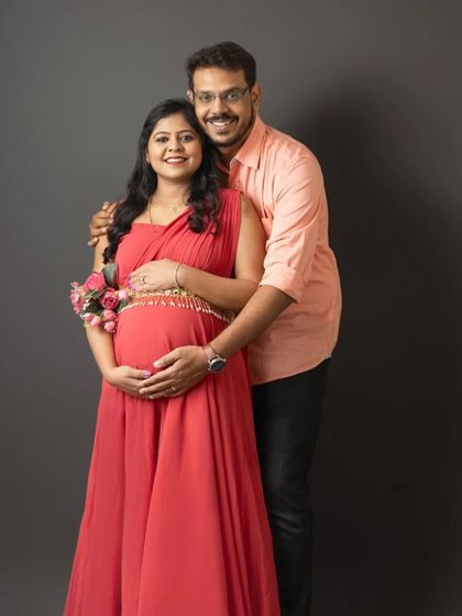 A beautiful couple's maternity portrait. The expecting mother in her red gown is complemented by fresh flowers, adding a touch of natural elegance to the shot.