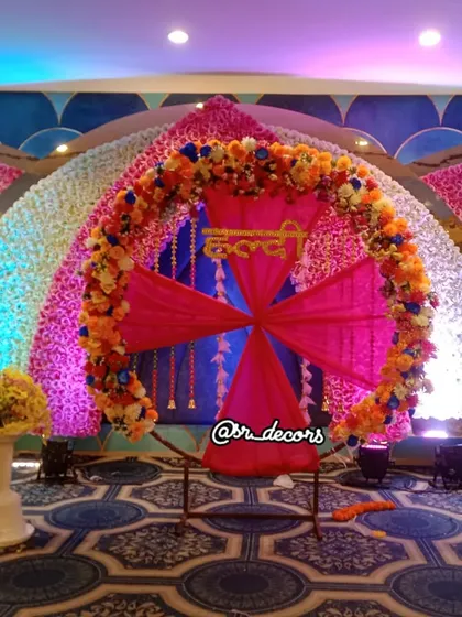 For a grand Haldi function, I can create a stunning stage like this one. It features a massive floral ring, a backdrop of flower walls, and a central seating area, making it the perfect spot for all your ceremonies and photos.