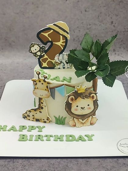 An "Animal in the zoo" cake with a giraffe, lion, and monkey. The number 2 topper is cleverly designed with a giraffe print.