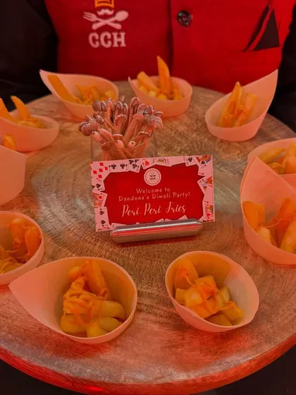 Crispy Peri Peri Fries served in individual paper cones on a rustic wooden platter. It's a simple snack, elevated with great flavor and thoughtful presentation for a games night party.