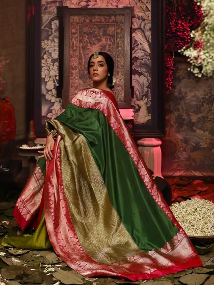 An editorial shot for Soho Begum, featuring a model in a stunning green and red Banarasi silk saree, creating a rich, painterly look.