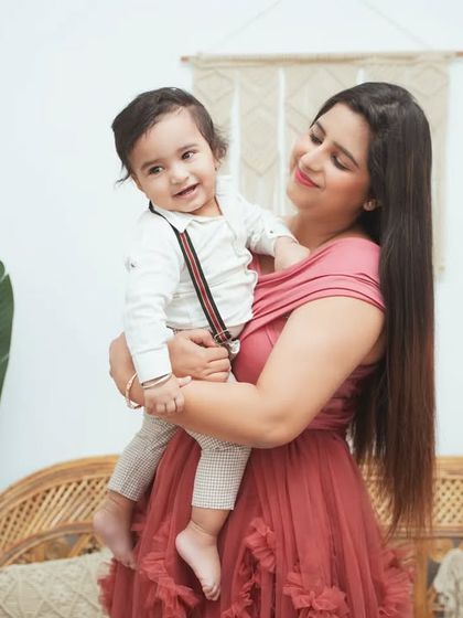 A mother holds her smiling baby boy. Our boho studio setup provides a warm and inviting backdrop for mother and child portraits.