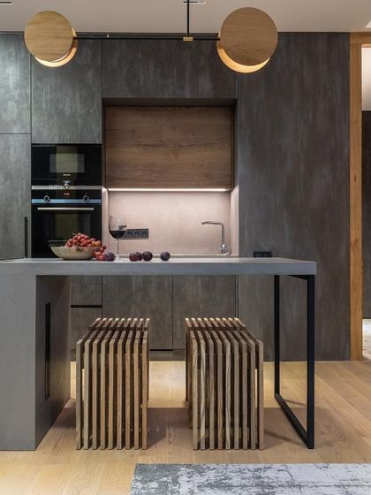 This kitchen achieves a seamless, industrial look with its concrete-finish cabinets and countertop. The wood accents and uniquely designed stools add warmth and texture to the minimalist space.